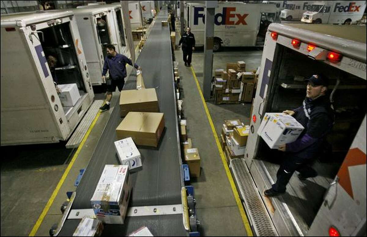 Couriers including Matt Klein, right, unload outbound freight Friday for FedEx in Seattle, which expects to clear out its backlog by today.
