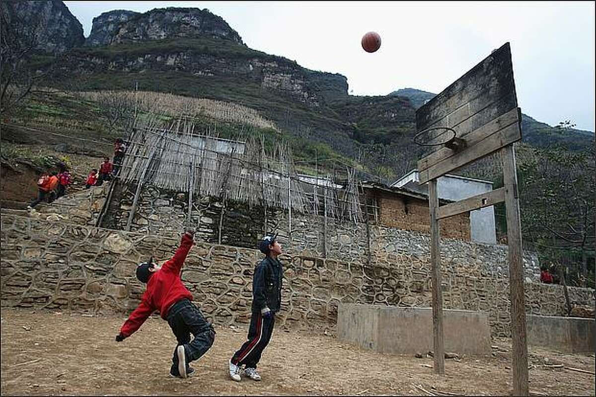 Students play basketball at their school in the village of Gulucan in Hanyuan county, Sichuan province, China. More than 60 farmers' families live in six isolated locations, perched high above a spectacular canyon in the area. Some farmers' children have to walk three hours to their school along the edge of a crumbling, narrow mountain path with a sheer 5,000ft drop on one side.