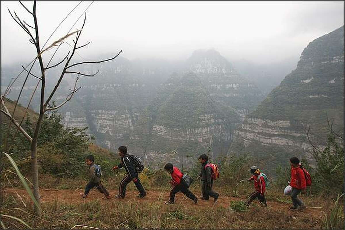 Schoolboys walk to their school in the village of Gulucan in Hanyuan county, Sichuan province, China. More than 60 farmers' families live in six isolated locations, perched high above a spectacular canyon in the area. Some farmers' children have to walk three hours to their school along the edge of a crumbling, narrow mountain path with a sheer 5,000ft drop on one side.
