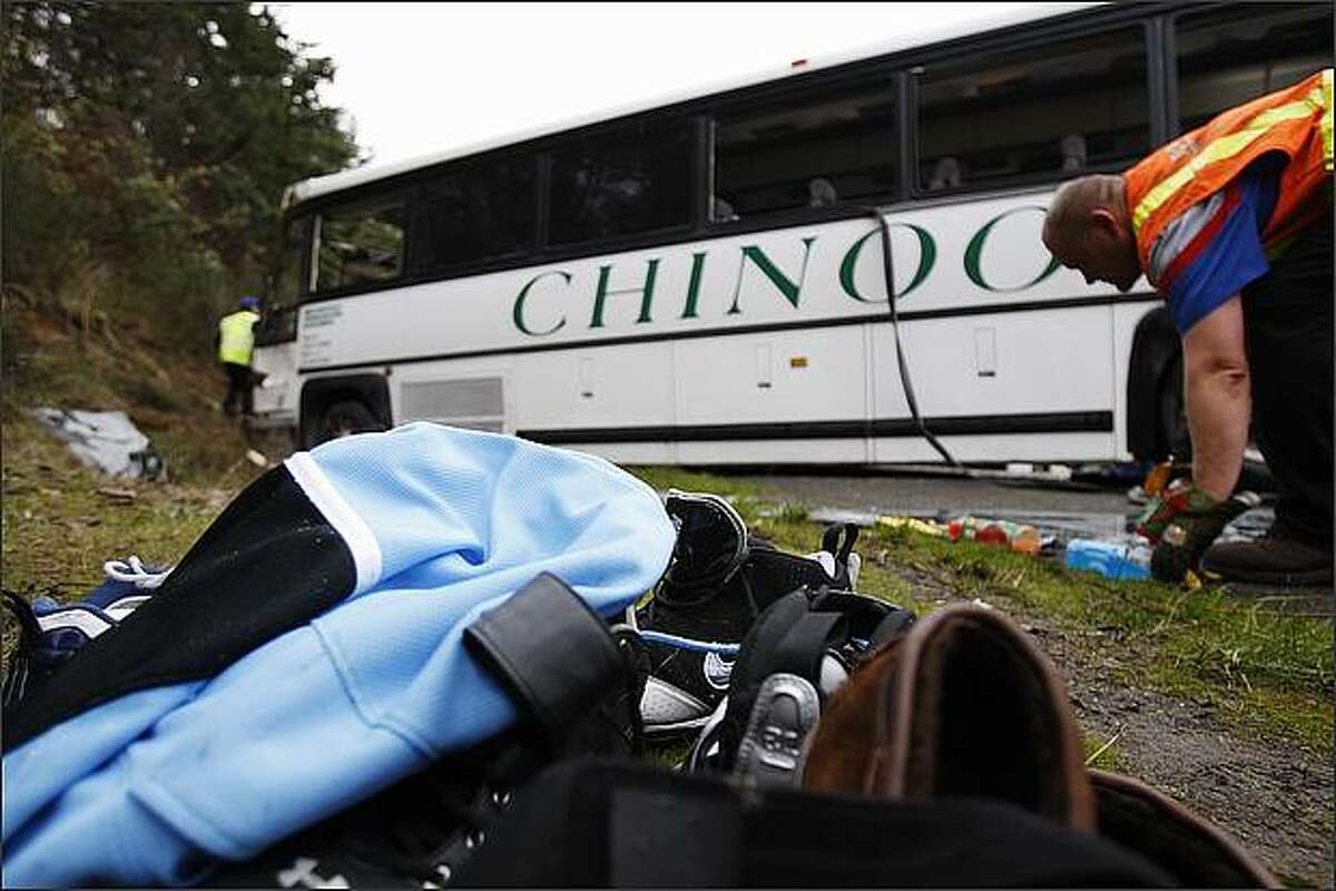Some personal belongings of Bellevue football players are stacked in front of a Chinook charter bus that was carrying the team to a playoff game when it overturned on Interstate 5 Friday morning.