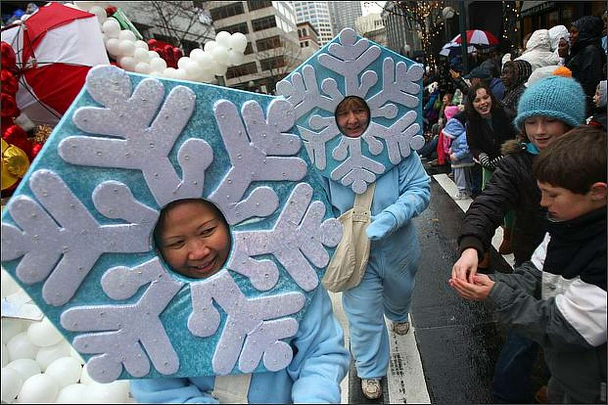 Snowflake-costumed characters accompany Santa's float and pass out candy during Seattle's annual Macy's Holiday Parade.