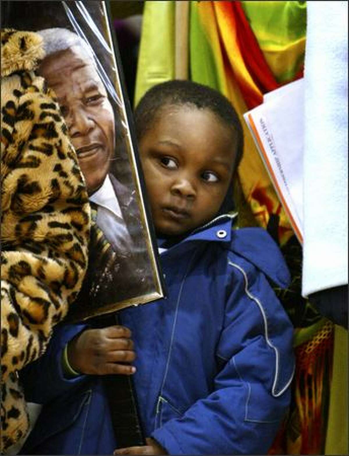 Davon Fuller holds a photo of Nelson Mandela as he squeezes in between his grandmother and older sister at the Franklin High School gym during the annual Martin Luther King Jr. Day celebration and march.Arias: Davon was just one of the hundreds who attended and later participated in the three-mile march that started at the high school and ended at Martin Luther King Jr. Park.