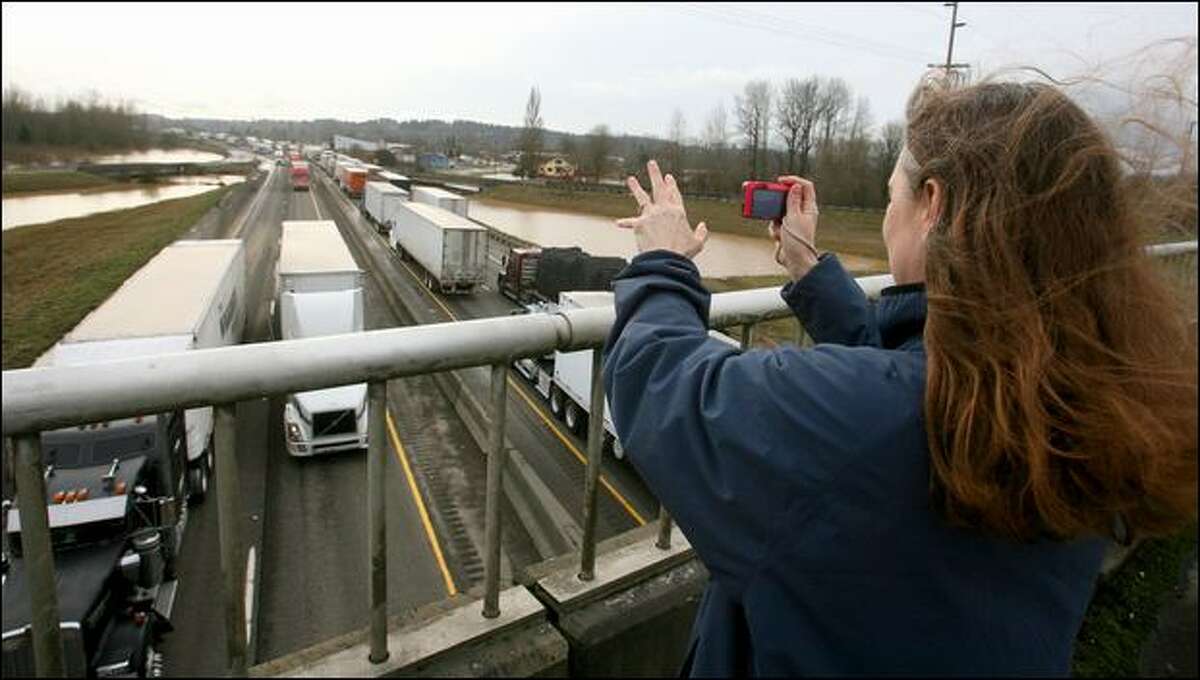 Melissa Sikel of Centralia waves and takes photos of passing trucks as a 20-mile stretch of I-5 reopened.