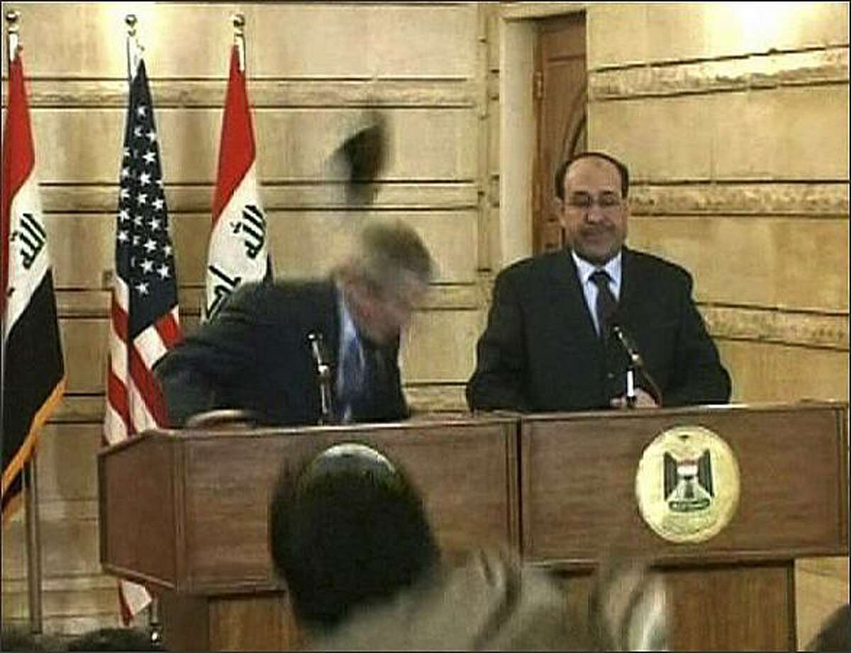 In this image from APTN video, a man throws a shoe at President George W. Bush during a news conference with Iraq Prime Minister Nouri al-Maliki in Baghdad. The man threw two shoes at Bush, one after another. Bush ducked both throws, and neither man was hit. (AP Photo/APTN)