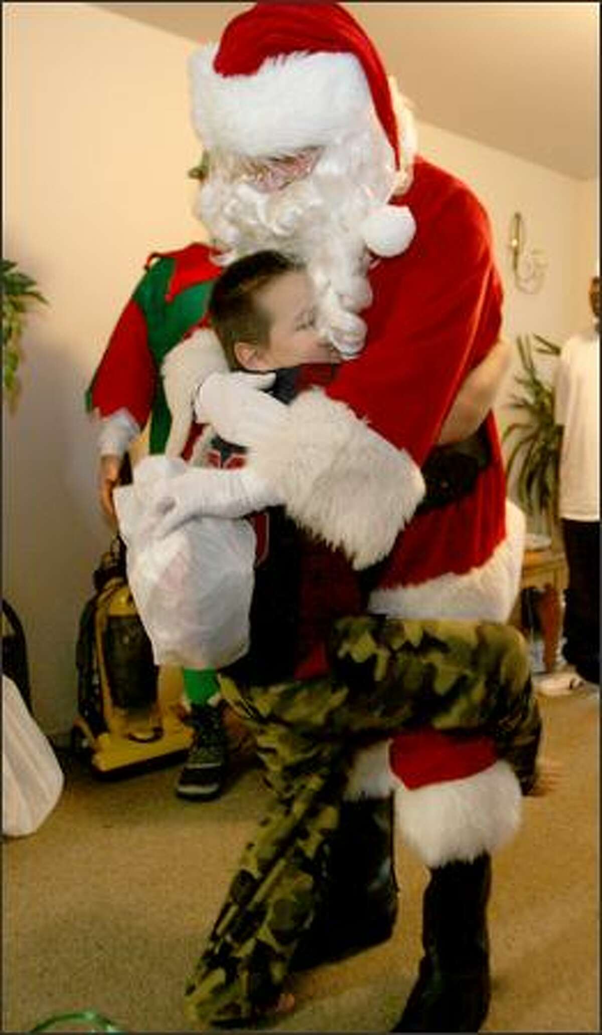 Although tenative at first, Aaron, 7, warmed up to Santa with the Forgotten Children's Fund as he gives him a big hug at his apartment in Seattle.