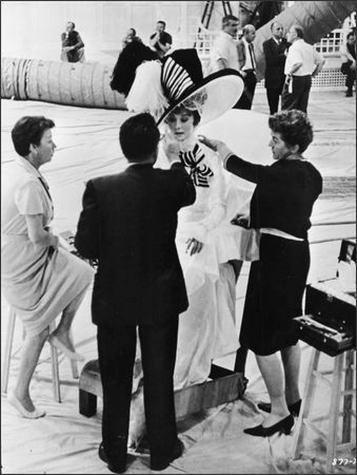 Belgian-born actor Audrey Hepburn (1929-1993) wears an elaborate costume while having her makeup done on the set of 'My Fair Lady,' directed by George Cukor, 1964.