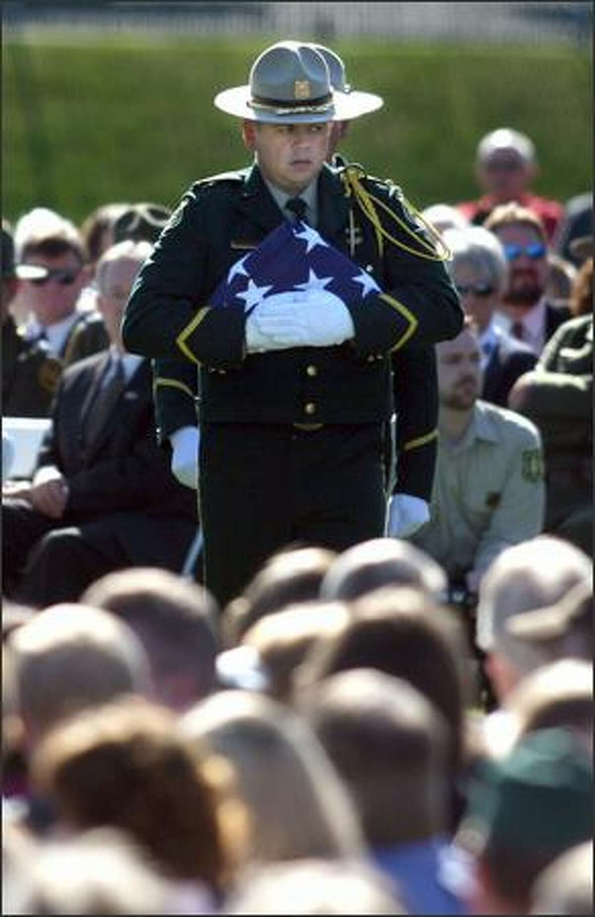 Forest Service officials prepare to unforld, display and refold an American flag to be given to Kristine Fairbanks' daughter, Whitney Fairbanks, during a memorial service for the slain officer in Port Angeles on Monday.