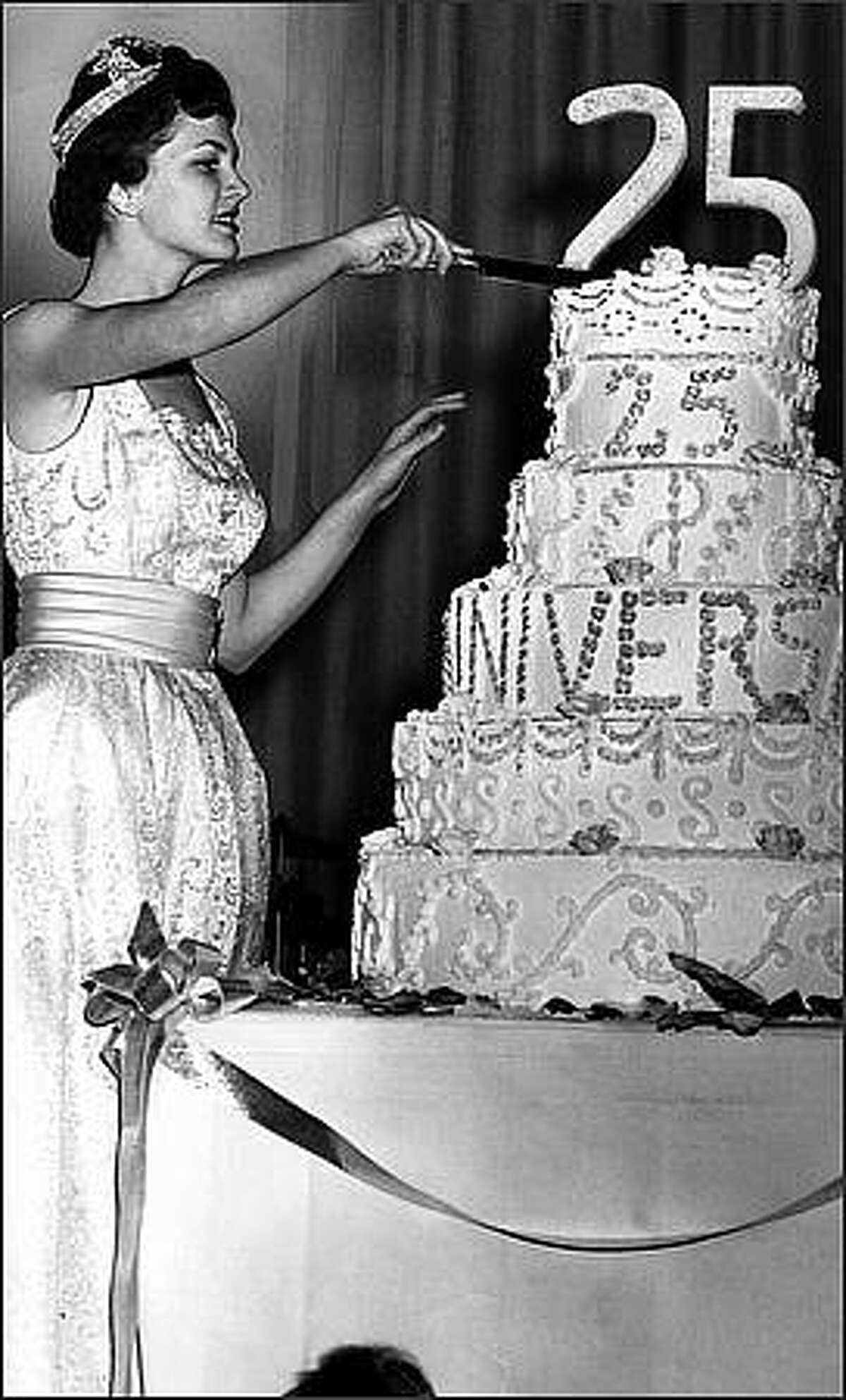 Seafair Queen Diane Gray carves the mountainous cake which marked the 25th anniversary of the popular sports banquet conceived by Post-Intelligencer Sports Editor Royal Brougham