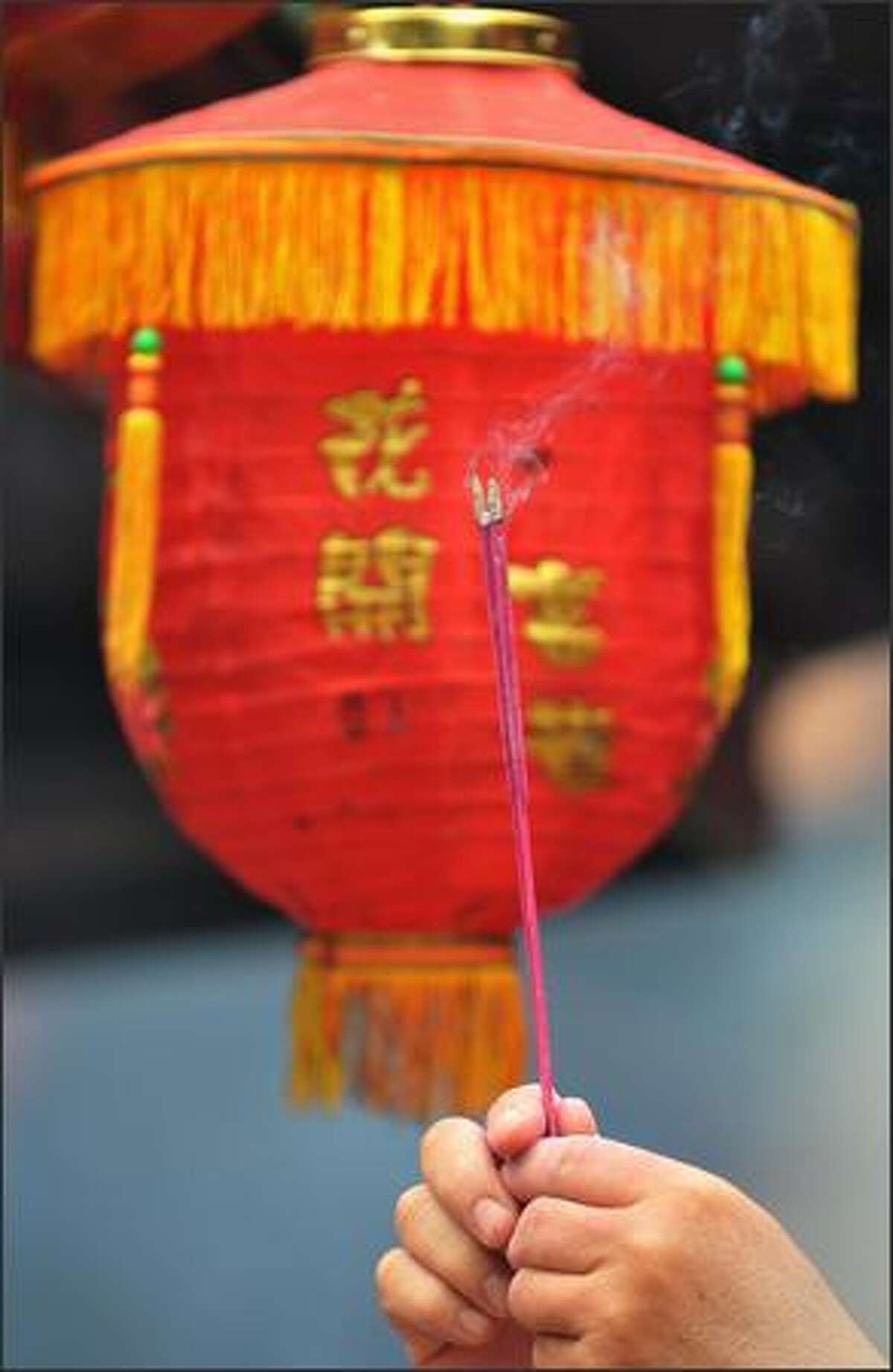 A worshipper holds incense sticks in front of a lantern during Chinese Lunar New Year prayers in Jakarta.
