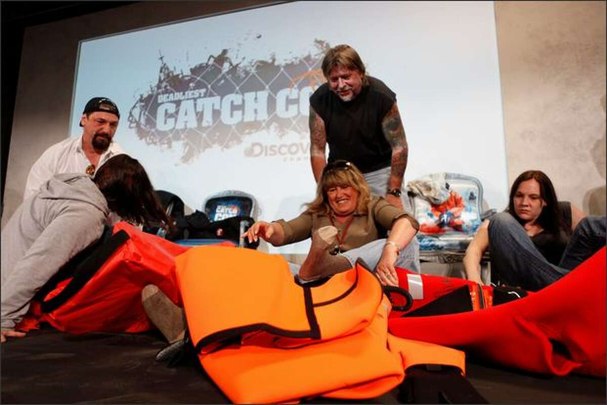 Ship captains Johnathan Hillstrand and Phil Harris help fans into survival suits in a speed dressing competition during CatchCon at the Bell Harbor Conference Center on Saturday in Seattle. (Thom Weinstein/Seattlepi.com)