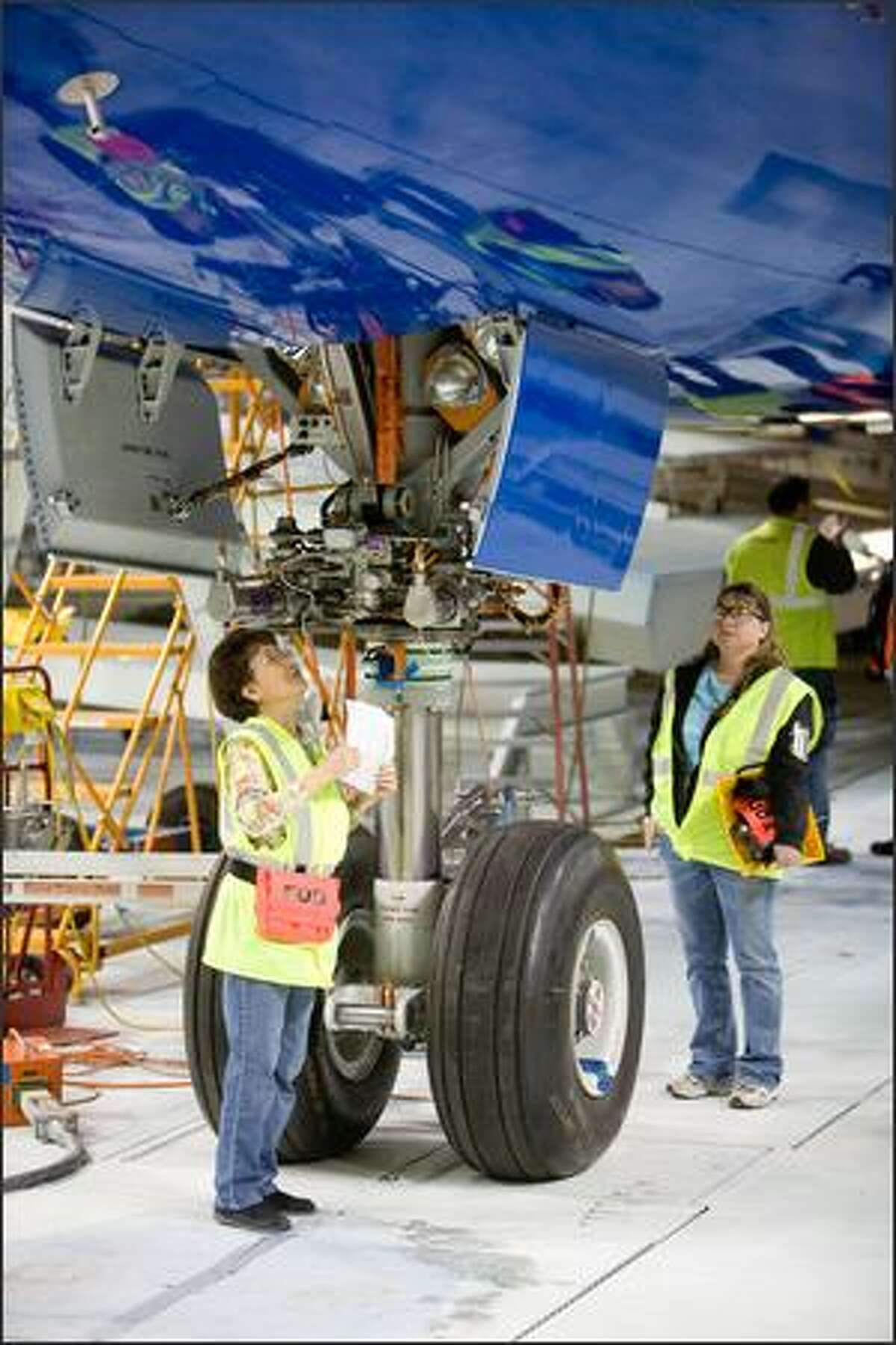 Workers, including Hui San Pang, left, test components of Boeing's first 787.