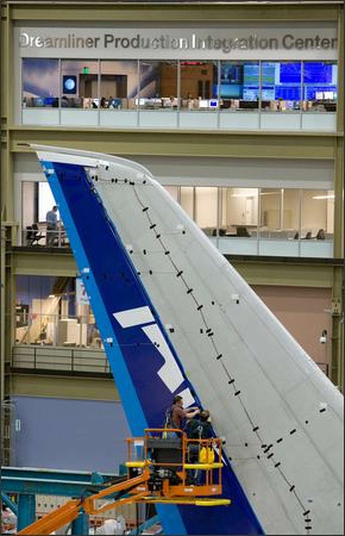 Workers attach parts to the tail of a Boeing 787.