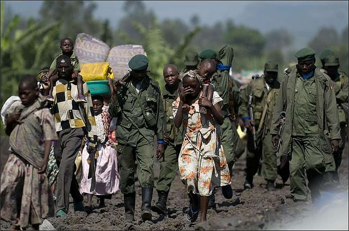Democratic Republic of Congo soldiers and Internally Displaced People march into the provincial capital of Goma, on October 29, 2008. Thousands of Congolese people arrived into Goma from the Kibati provisional camp where they arrived on Oct 27 after violence started between Forces loyal to renegade Laurent Nkunda and the Congolese army. Goverment forces are fleeing from the key eastern Democratic Republic of Congo city of Goma ahead of advancing rebels, military sources and residents said today. AFP PHOTO/Walter ASTRADA
