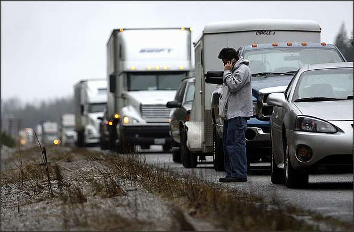Jonathan Gutierrez of Renton talks on the phone while waiting on the shoulder of I-90 where it was closed at North Bend due to heavy snowfall on Snoqualmie Pass on New Year's Day. Gutierrez was trying to drive to Spokane for work. He was planning to wait on the shoulder for three hours before turning around in hopes that the pass would be reopened.