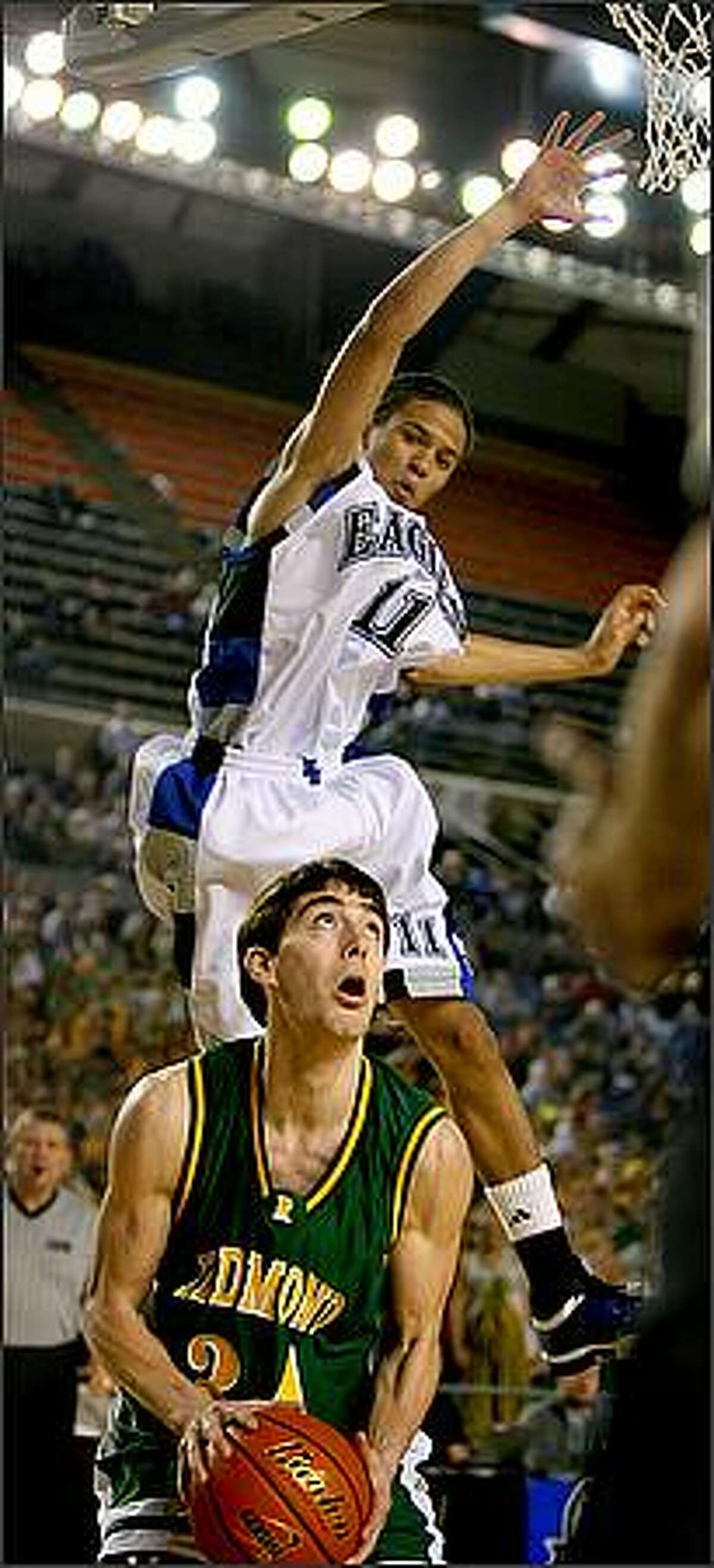 Federal Way's Michael Hale gets some elevation as he is faked by Redmond's Chad Hui-Peterson in the first quarter as Federal Way High School battles Redmond High School in the first round of the WIAA Boys' State Basketball Championships at the Tacoma Dome in Tacoma, Wash.