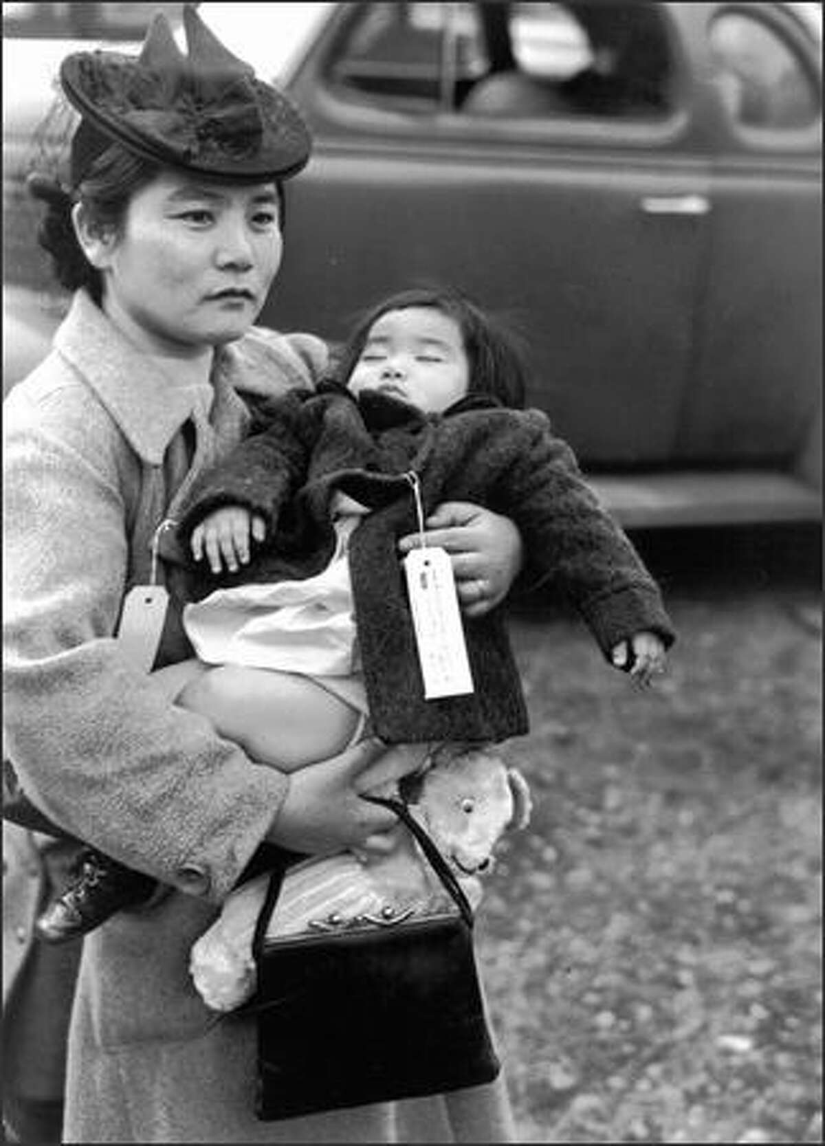 Her 11-month-old daughter asleep in her arms, Fumiko Hayashida waits to board a ferry from Bainbridge Island on March 30, 1942. The pair were being deported to an internment camp for Japanese-Americans in Manzanar, Calif.