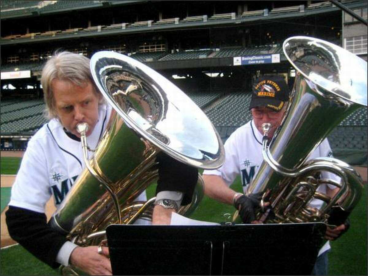 Tuba players Mark Lloyd, left, and Michael Russell, retired principal tuba player for the Seattle Symphony Orchestra, practice for their performance Tuesday at the Mariners home opener.