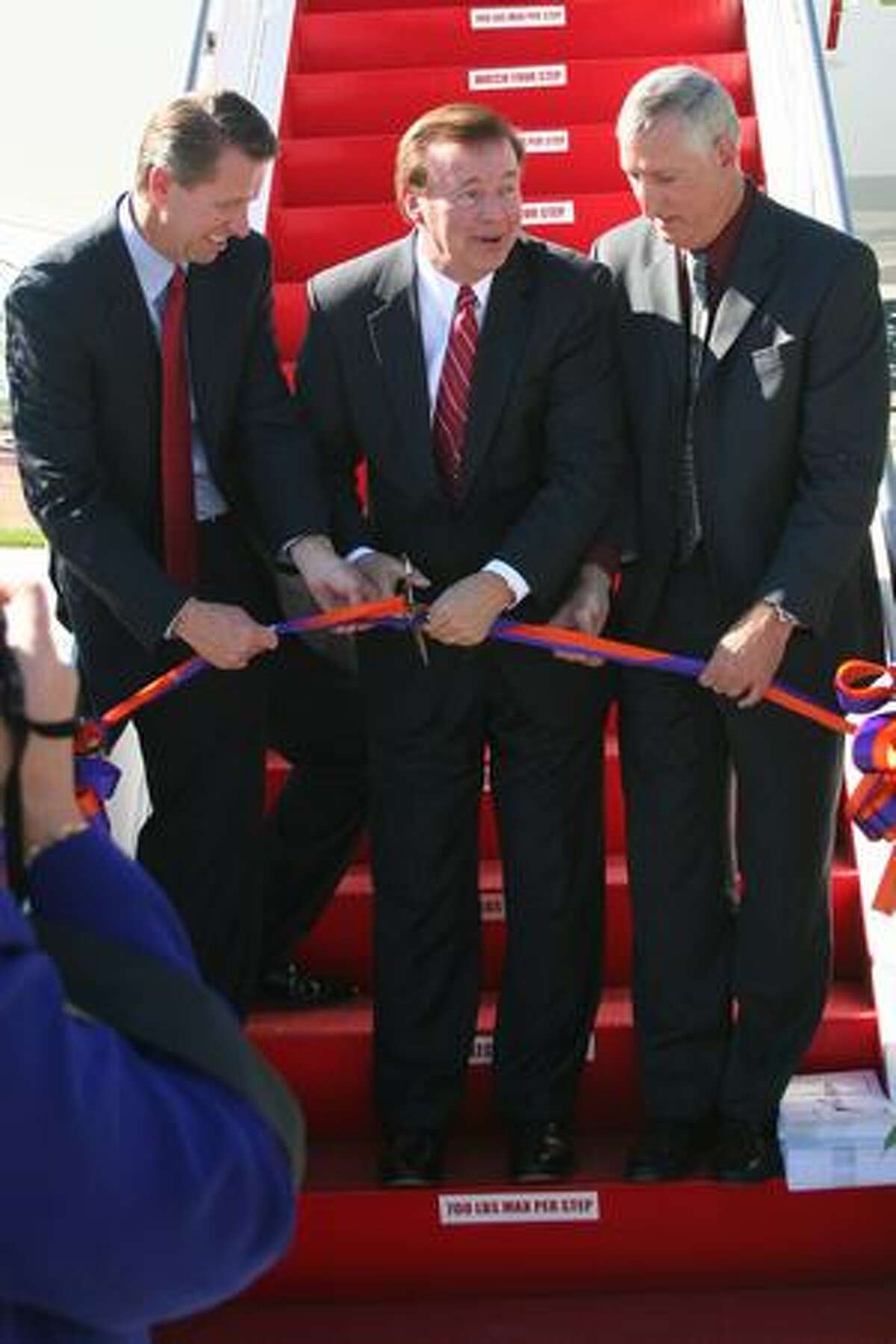 David Bronczek, president and chief executive of FedEx Express, has trouble cutting the ribbon on FedEx's first Boeing 777 Freighter. Kevin Schemm, vice president of North America sales for Boeing Commercial Airplanes (left), and Larry Loftis, general manager of the 777 program, hold the ribbon. Boeing delivered the freighter on Sept. 22, 2009.