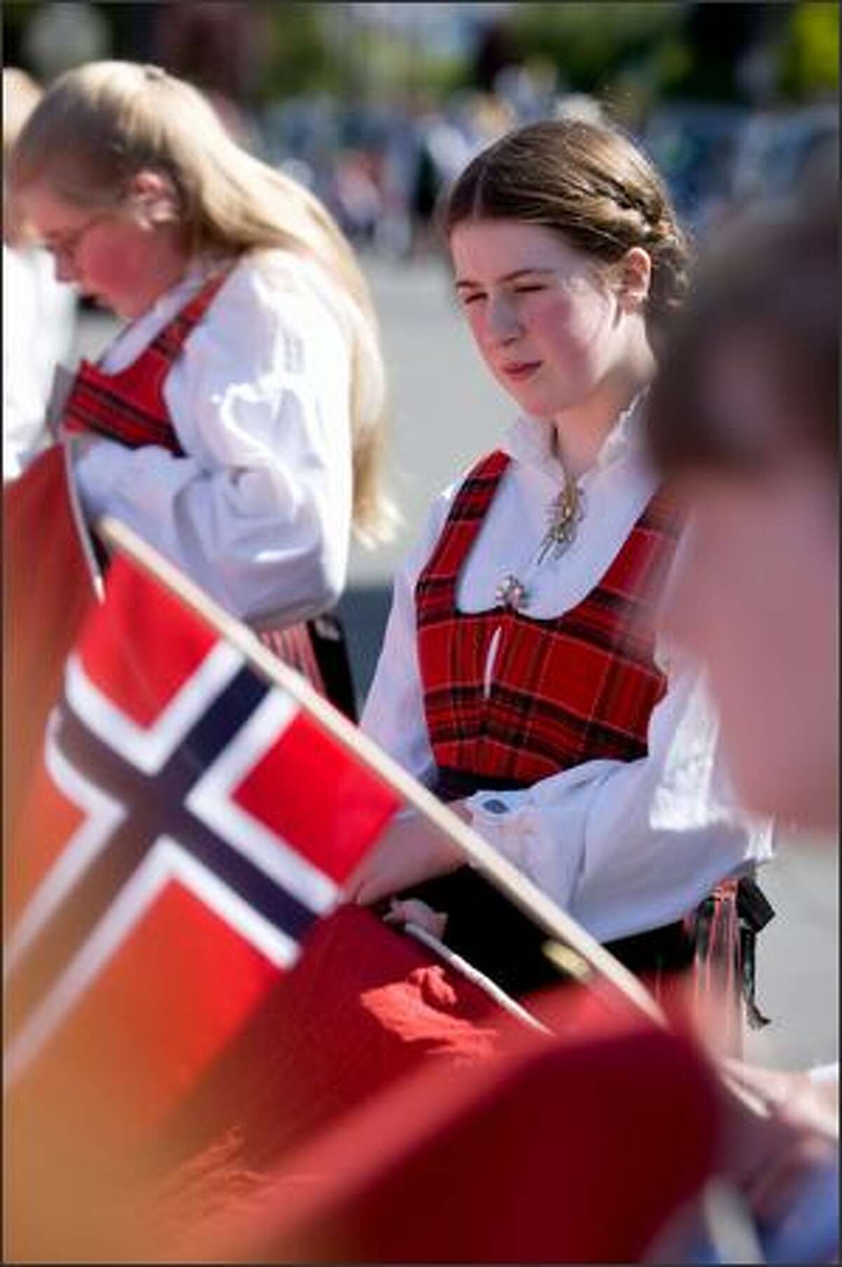 Anna Ripley, 12, relaxes alongside sister Tera Jane, 13, left, before the start of the Norwegian Constitution Day parade in Ballard.