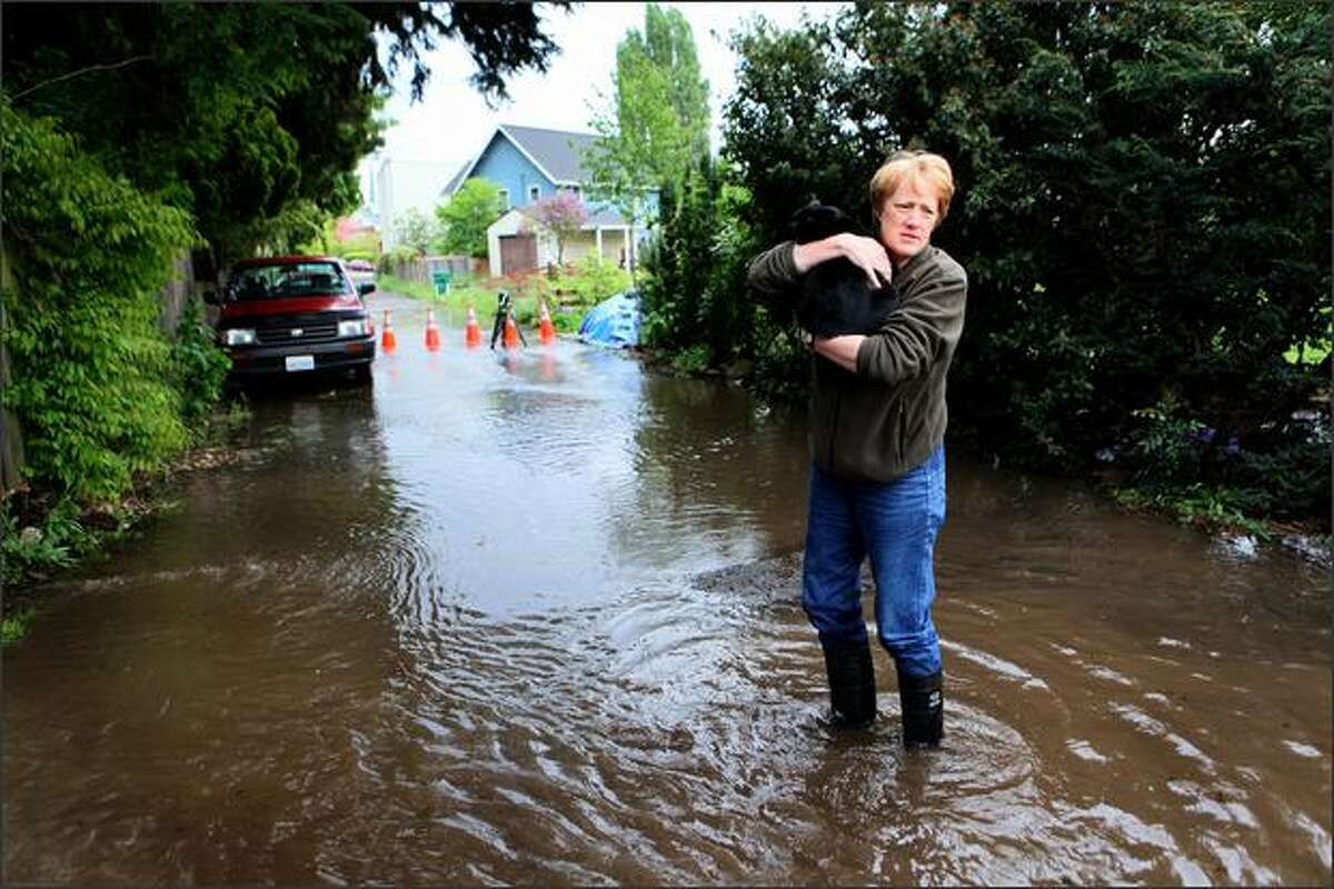 A neighbor holds a cat removed from a flooding home after a water main burst on Tuesday in Seattle's Ravenna neighborhood.