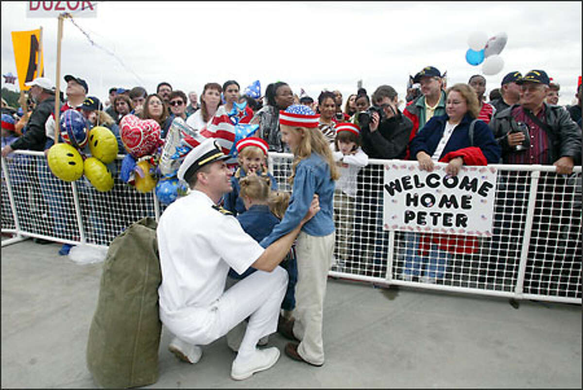 Lt. Cmdr. A.J. Reiss, of Port Orchared, is greeted by his four daughters -- Dasha Reiss, 8 (standing, right); Julia, 5; Emma, 3; and Annie, 2 -- after the USS Carl Vinson returns to Bremerton after eight months at sea.