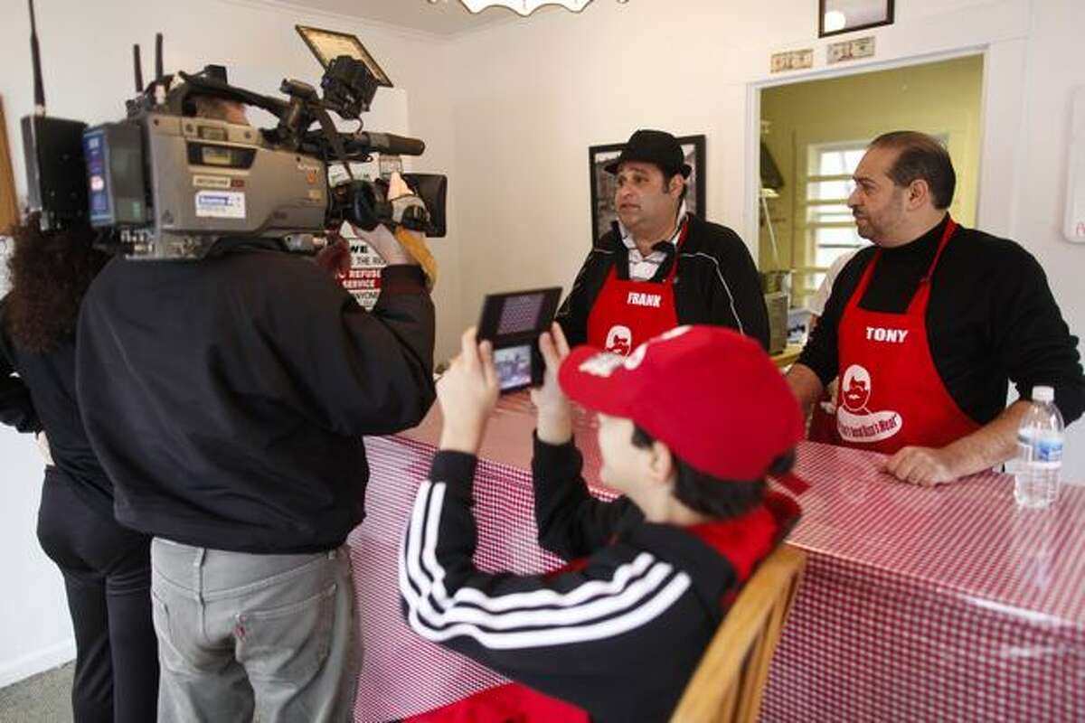 Sonny Rizzo takes a photo of reporters interviewing his father, Frank, at Rizzo's French Dip in Crown Hill.