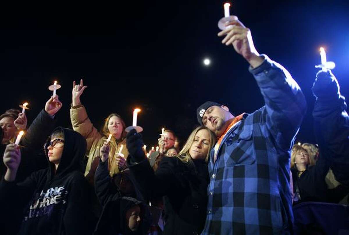 Jesse Clarke, right, and Bobbi Jo Lundt of Lakewood raise their candles during a candlelight vigil on Wednesday December 2, 2009 at the Lakewood Family YMCA in Lakewood, Wash. Thousands gathered to pay their respects to four Lakewood Police officers who were shot and killed at a coffe shop Sunday morning in Parkwood.