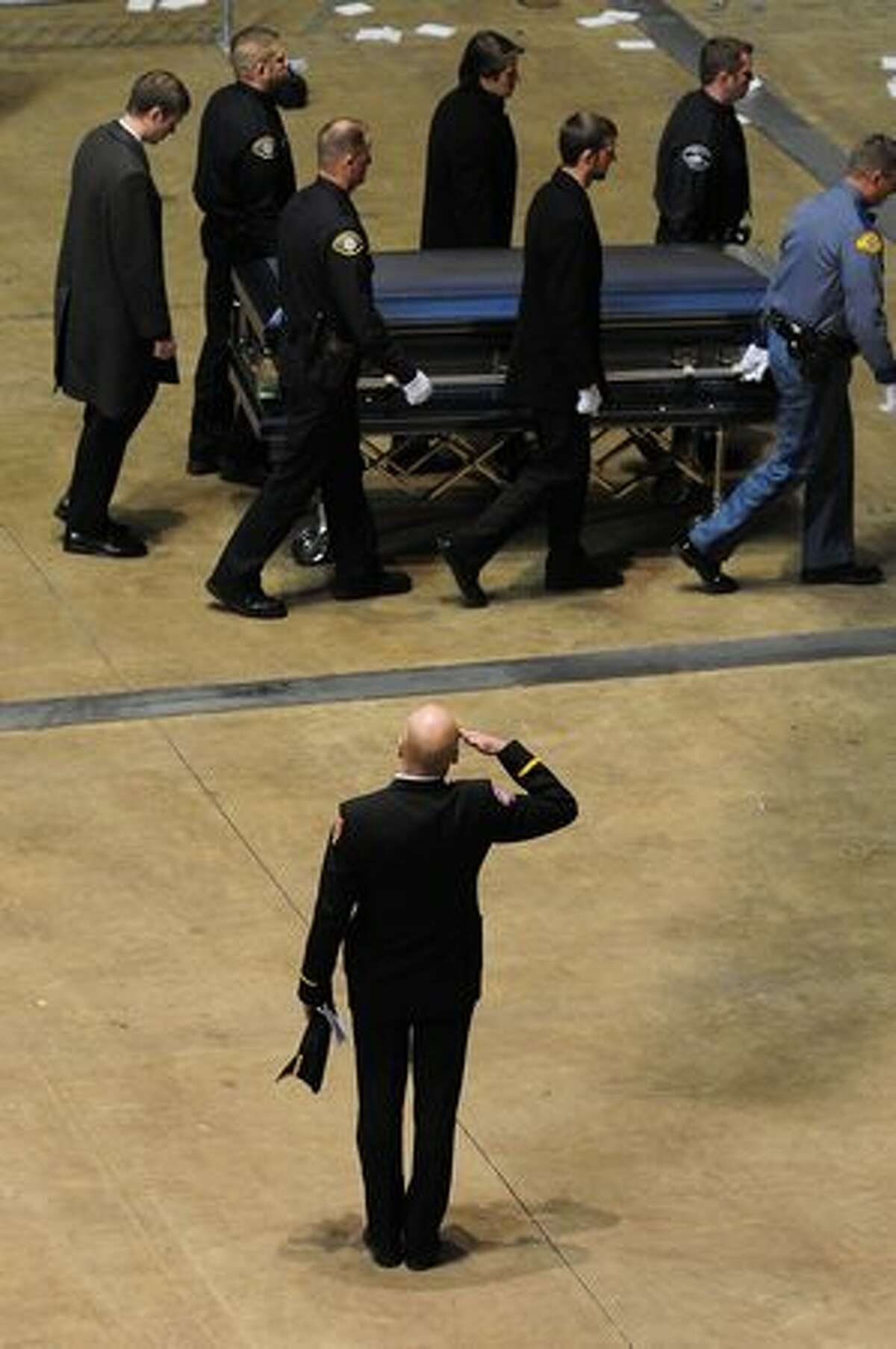 An officer salutes as a casket is removed following a memorial service for four slain police officers in Tacoma.