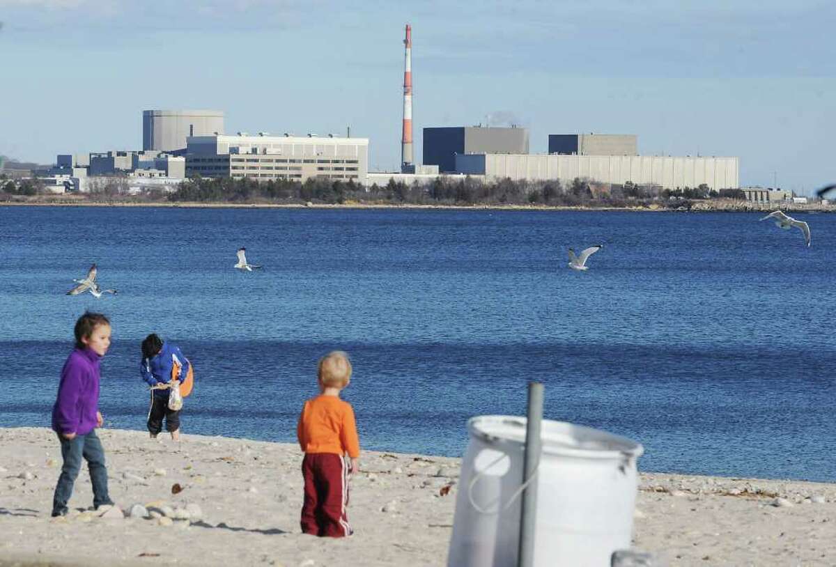 Families play on the beach with the Millstone Nuclear Power Plant in the background in Niantic, Conn. on Sunday March 20, 2011.