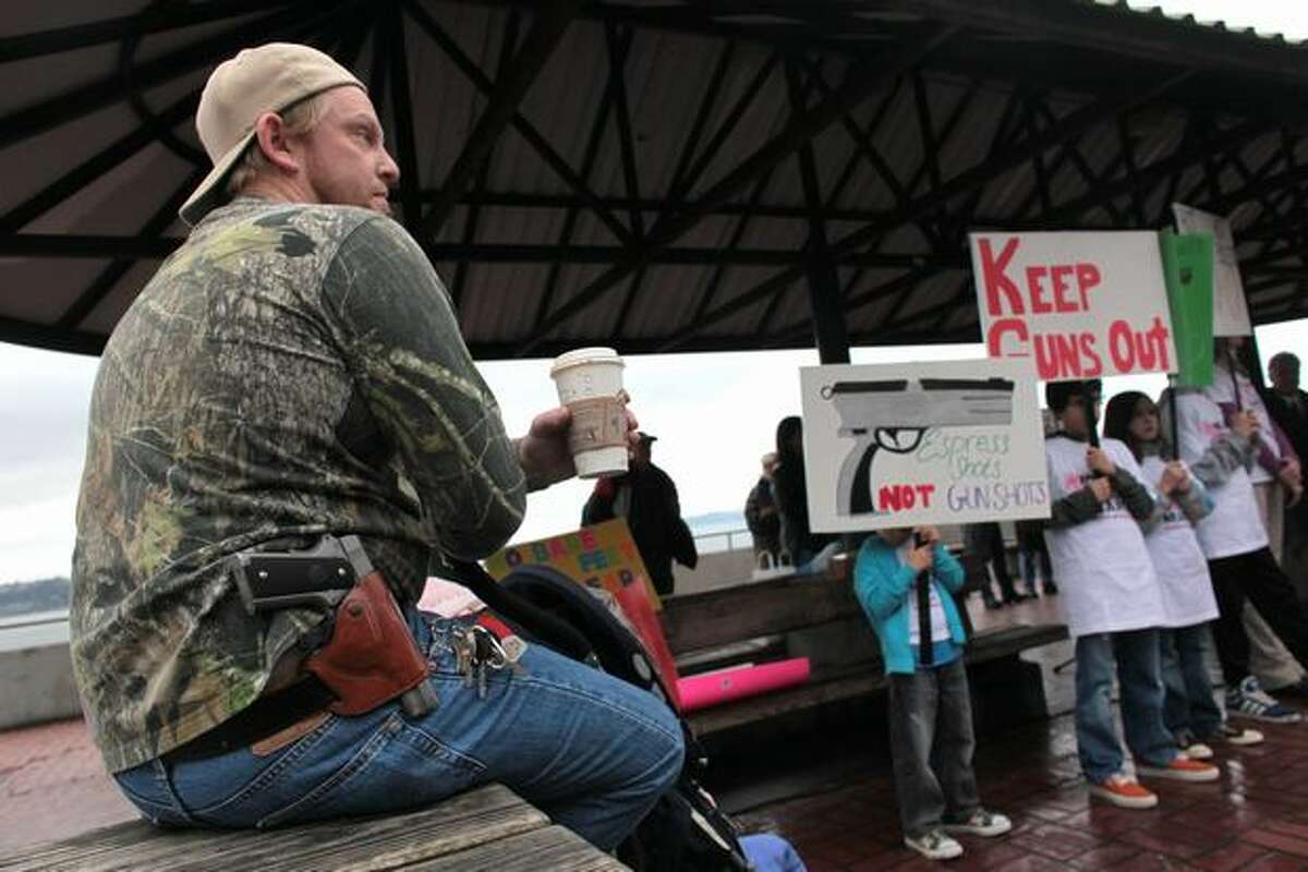 Greg Dement, of Kent, shows his opposition to gun-control advocates by wearing a Colt 1911 during a press event at Victor Steinbrueck Park organized by Washington CeaseFire, the Brady Campaign to Prevent Gun Violence, and Washington State Million Mom March. Organizers of the event hope to pressure Starbucks into adopting a no-guns policy in all its stores.