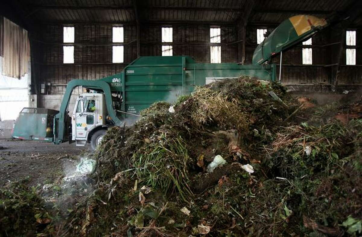 A truck delivers yard waste and food scraps collected from King and Snohomish counties into the Tipping Building at Cedar Grove's composting facility in north Everett on Wednesday. The piles of compostable material steam as they generate heat and begin the composting process. Nick Harbert of Cedar Grove says the process is initially sped up this time of year because of grass clippings added to the mix by homeowners.