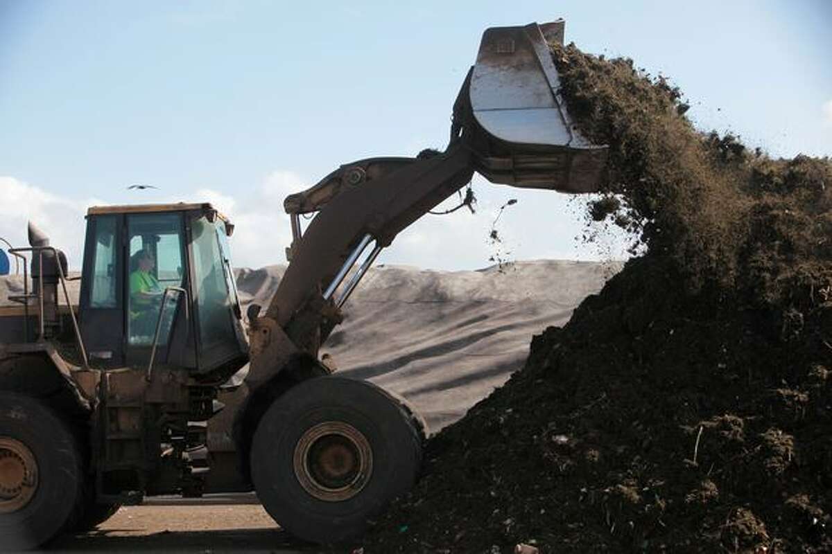 A front-end loader is used to pile ground yard and food waste into rows.