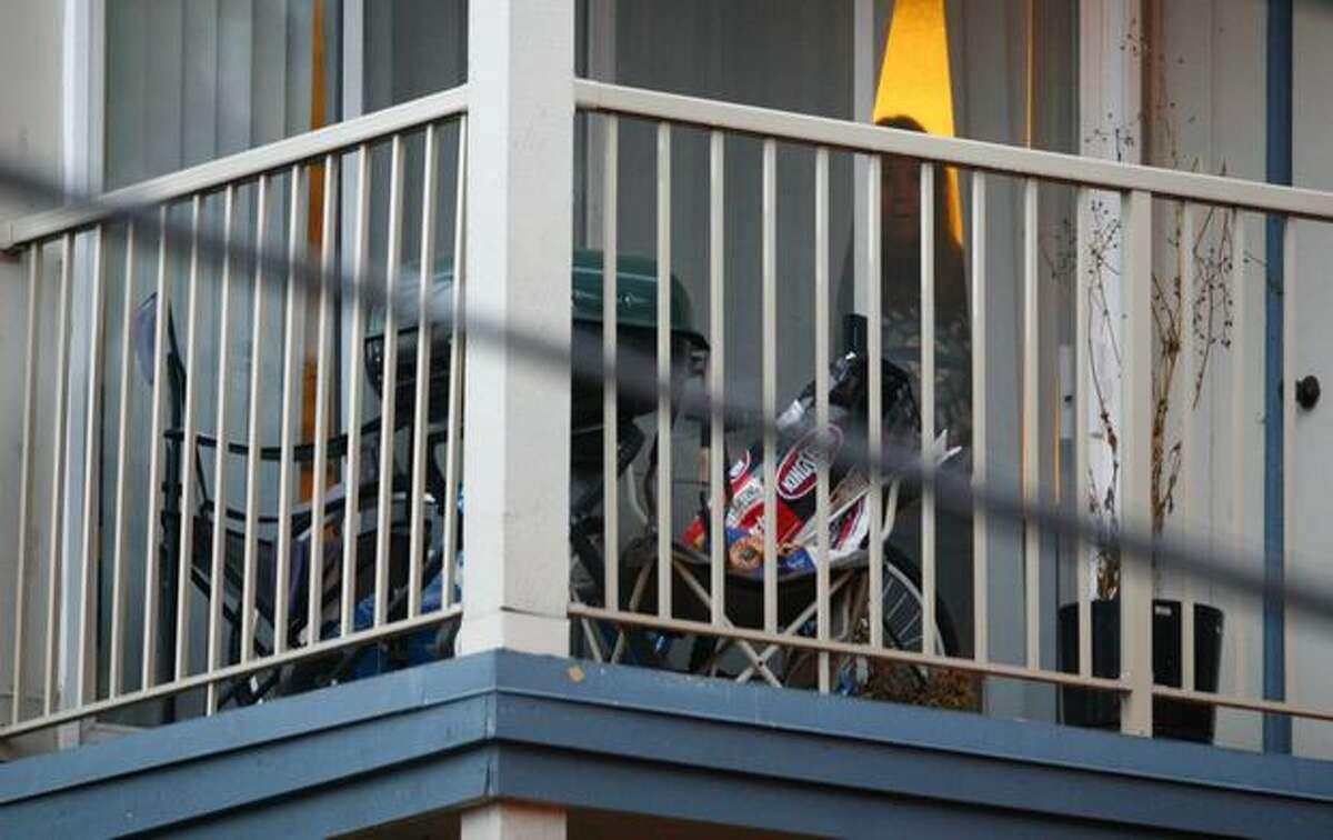 A woman peeks from her apartment as SWAT officers converge on the scene where a man was shot by police officers after he was investigated as a person of interest in the killing of Seattle Police Officer Timothy Brenton.