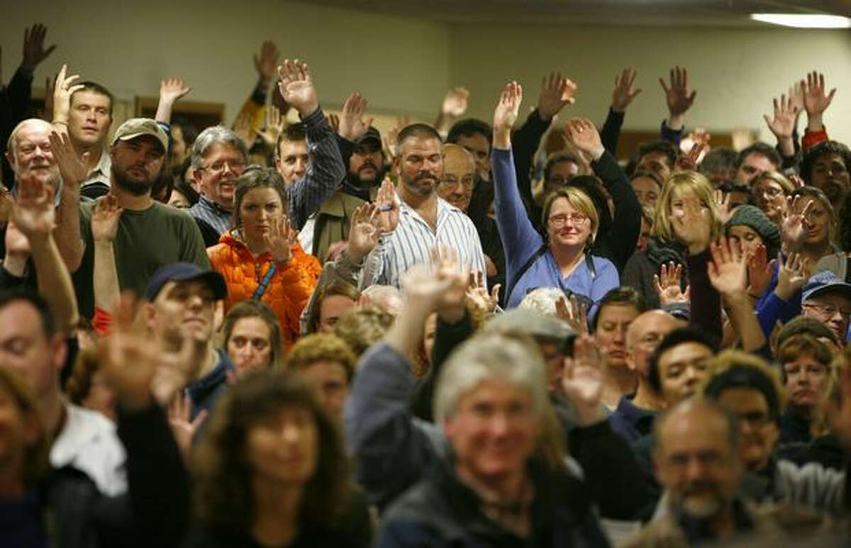 Some of the estimated 800 people who gathered Tuesday for the first of two community meetings at Phinney Ridge Lutheran Church raise their hands when asked if they have smoke detectors. The neighborhood had two meetings to discuss a rash of recent arsons that have the community on edge. Fourteen recent fires have been blamed on arson, one of the fires destroying three businesses and damaging others.