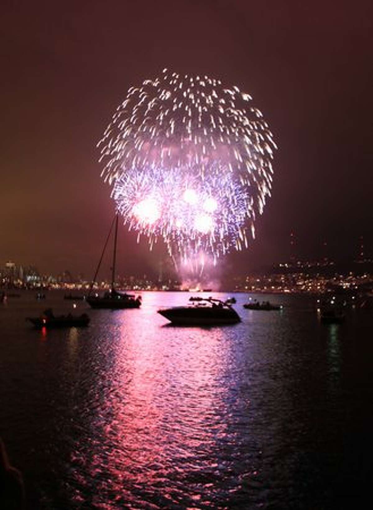 Fireworks explode over Lake Union - and hundreds of boats floating on the lake - during Seattle's Family Fourth celebration.