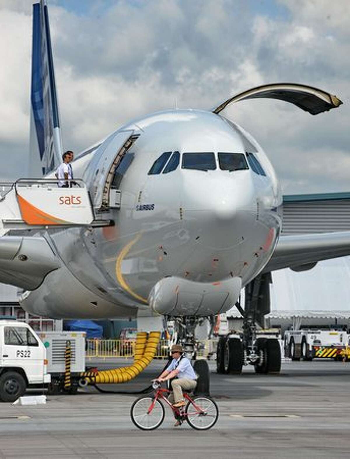 A cyclist rides past an Airbus A330-200F cargo plane for the static display at the Singapore Airshow on Feb. 1, 2010.