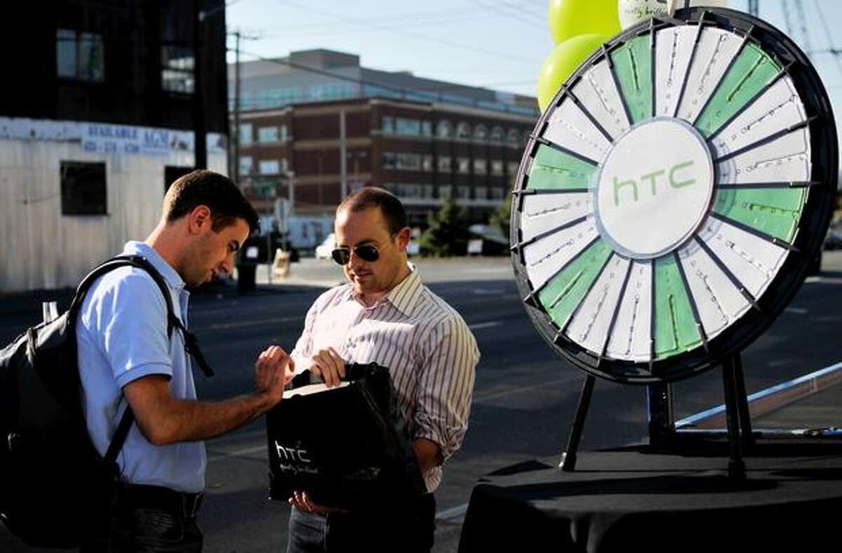Rickey Bird gives Michael Delisi several grab-bag options after Delisi spun the HTC prize wheel at the entrance of gdgt live in Seattle.