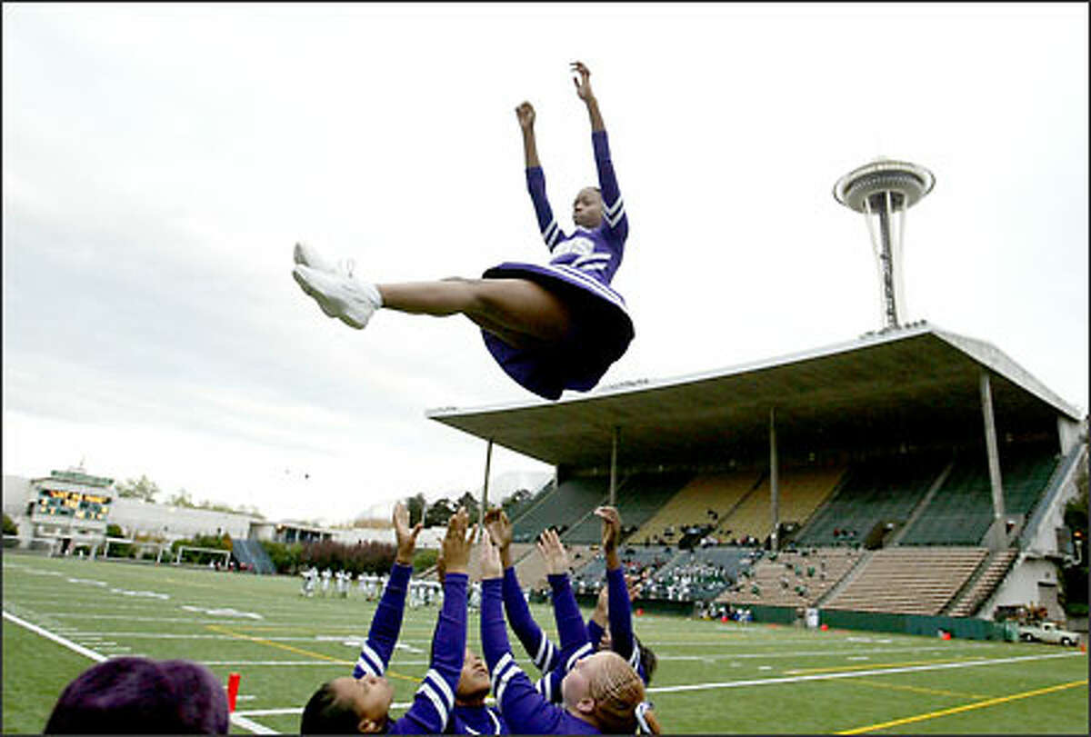 Garfield High School cheerleaders toss junior Zakiya Linzsey as they practice their routines prior to their game with Franklin at Memorial Stadium in the shadow of the Space Needle.