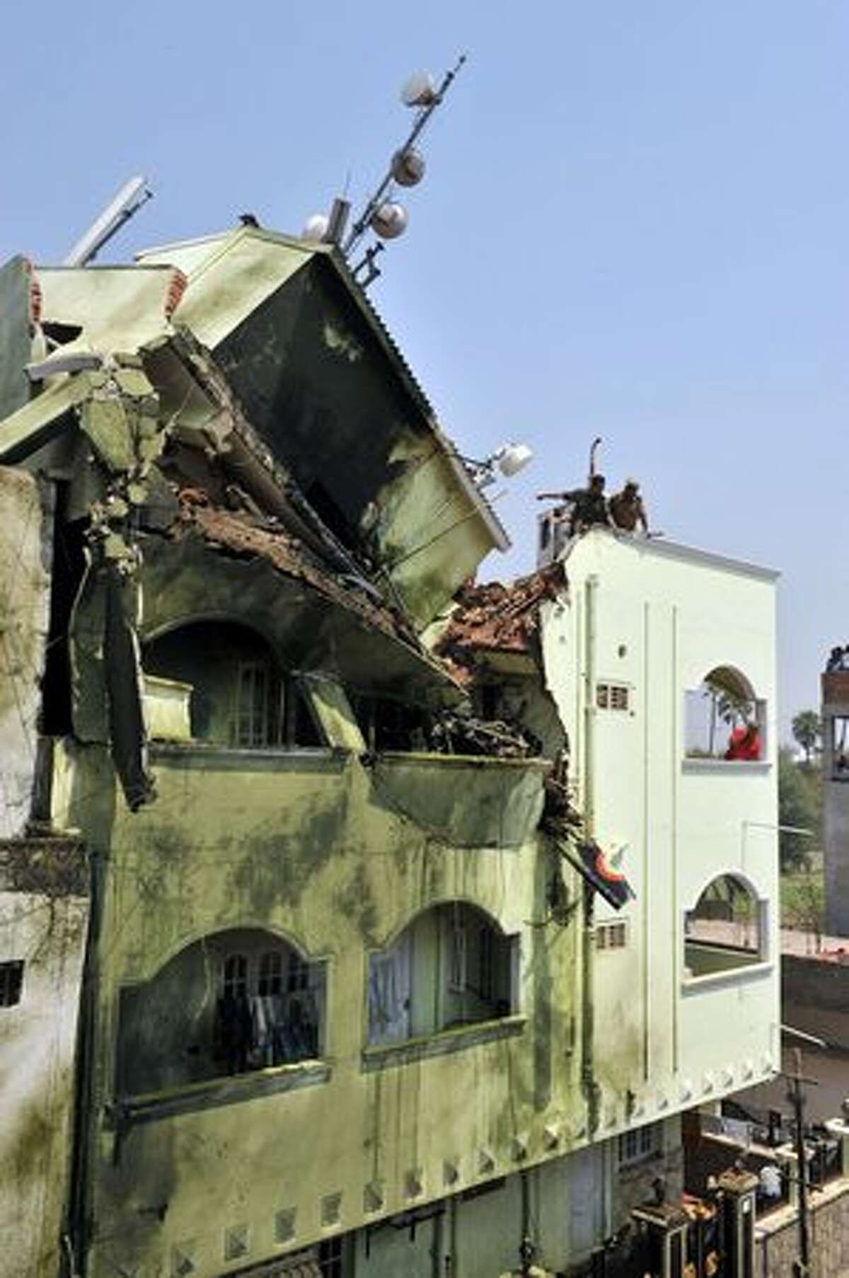 Indian residents and rescue officials search the wreckage of a building after an Indian Naval aircraft from the Aerobatic Team 'Surya Kiran' crashed during the India Aviation 2010 show at Begumpet Airport in Hyderabad on March 3, 2010. A navy aircraft taking part in an acrobatics show on the first day of an air show in the southern Indian city. The plane, a two-seater Kiran MK-II built by the state-run Hindustan Aeronautics, was part of a four-plane formation when it crashed. The accident occurred on the opening day of the India Aviation 2010 show, a five-day civil aviation exhibition.