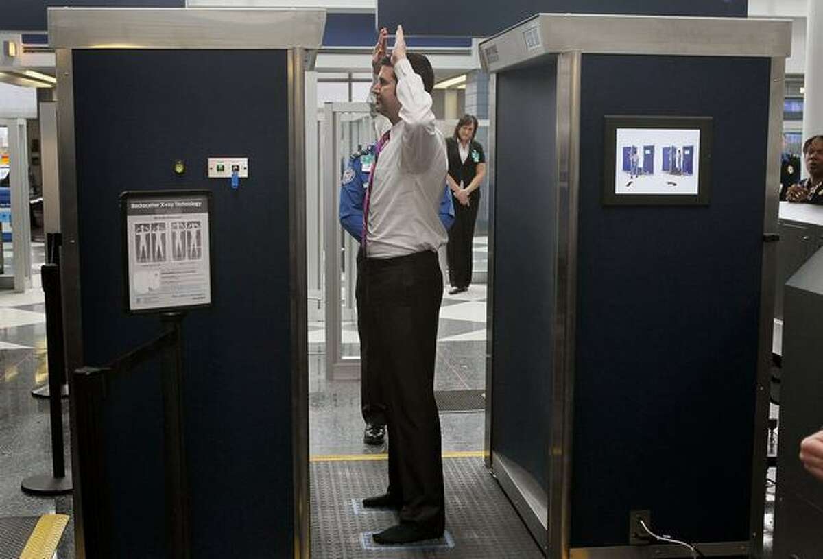 A Transportation Security Administration volunteer demonstrates a full-body scanner at Chicago O'Hare International Airport.
