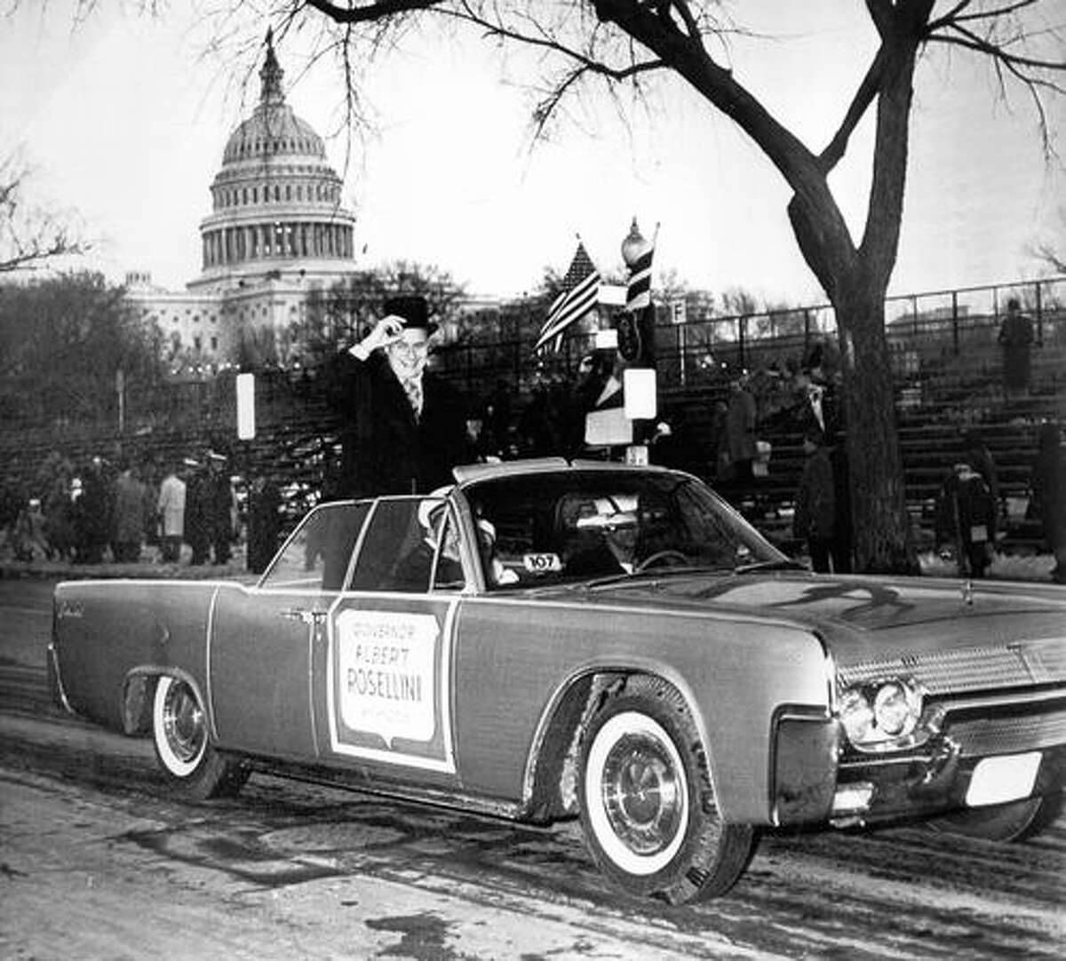 The January 1961 photo caption read: Smiling Gov. Albert Rosellini puts his hand to his heart as he acknowledges cheers from spectators along Constitution Avenue, part of inaugural parade route today.