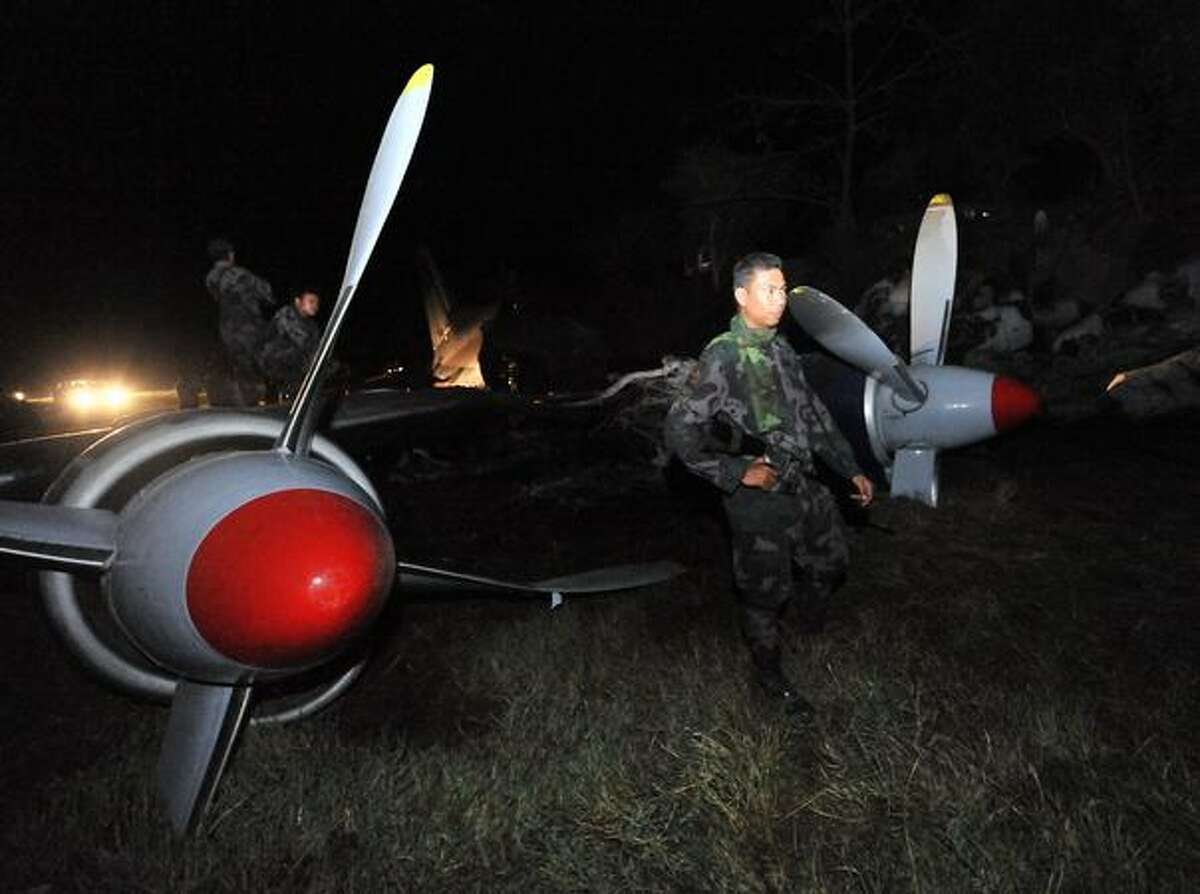 A policeman stands guard next to the wreckage of an Antonov 12 cargo plane early on Thursday, April 22, 2010. The plane crashed on a rice field late Wednesday, April 21 while trying to land at nearby Clark airport in the town of Mexico, in Pampanga province, north of Manila, Philippines. Three crew members were killed. (TED ALJIBE/AFP/Getty Images)