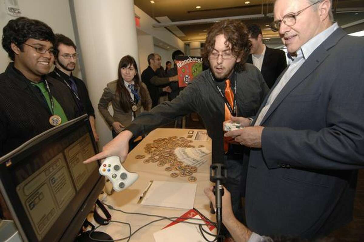 Members of Tufts University’s team AwesomeSauce give Craig Mundie, Microsoft’s chief research and strategy officer, a quick tutorial of their game Nanobots! before he tries it out. (Microsoft photo)