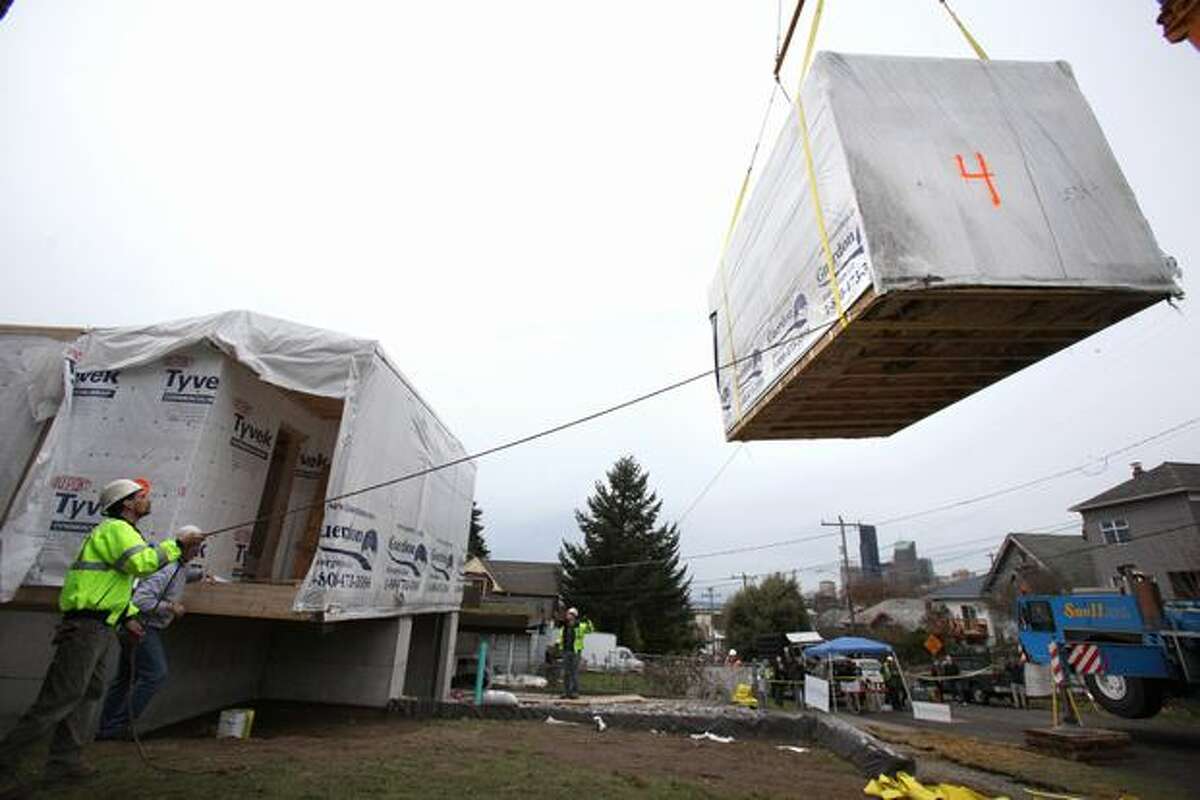 A crane positions a second-floor section of the Greenfab modular home.
