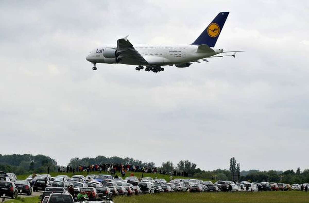 Spectators standing next to the village of Rheinmuenster, southern Germany, look to an Airbus A380 of German airline Lufthansa flying towards the airport of Baden-Baden during a landing training for pilots on May 31, 2010. The German national football team will use this A380 when they travel on June 6, 2010 to South Africa to take part in the 2010 Football World Cup.