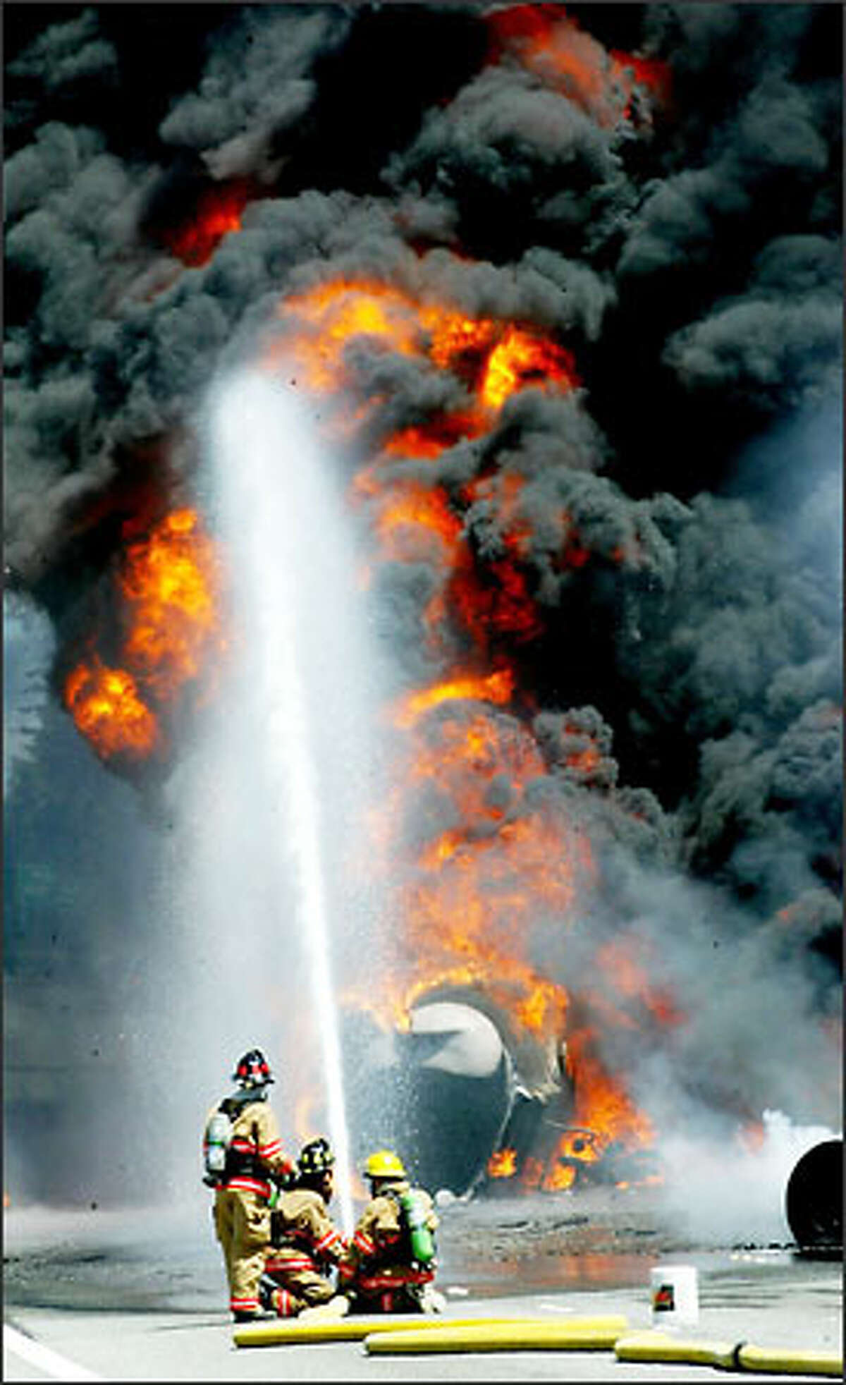 Lynnwood firefighters train a hose on flames and smoke pouring out of a burning tanker truck on an I-5 overpass in Lynnwood Saturday. The freeway was closed for hours.Haller: "I was in Edmonds on my day off when I noticed a huge black column of smoke soaring high over Lynnwood. A fuel truck had crashed and caught fire in the northbound lanes of I-5 over 44th Avenue West. I was amazed that it was still burning by the time I found a way to get on I-5 and photograph members of the Lynnwood Fire Department trying to knock down the flames. After units from Boeing's Paine Field fire department in Everett arrived and smothered the flames with foam and the fire was out, I was ordered to move back by a Washington State Patrol officer."