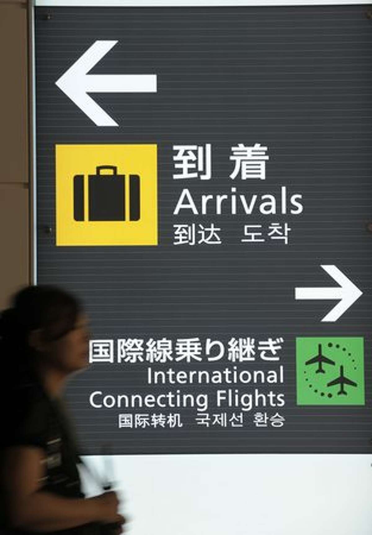 A woman walks in front of signage inside the new international terminal building at Tokyo International Airport. The terminal is scheduled to open on Oct. 21 this year.