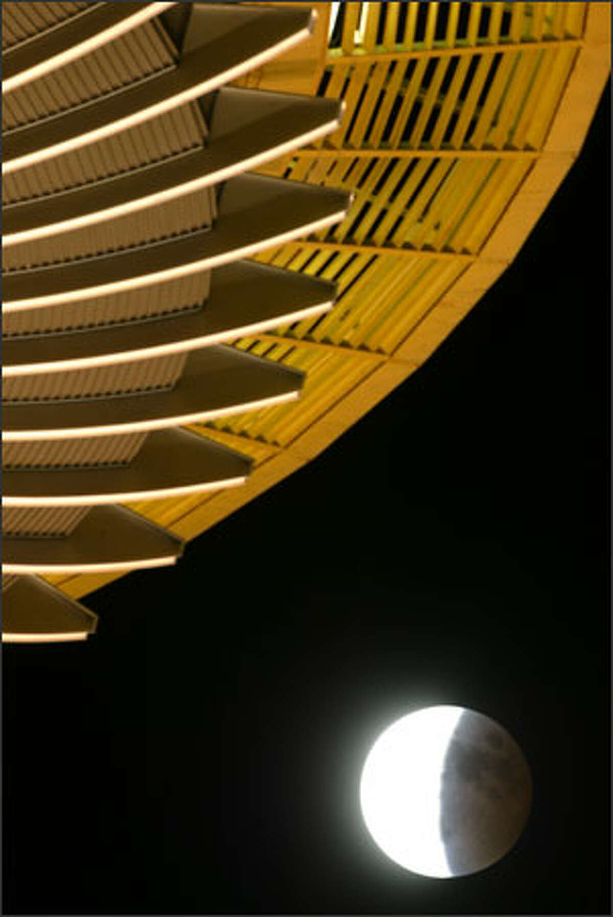 The moon emerges from the earth's shadow as it moves southeast through the Seattle sky during Wednesday's lunar eclipse, as viewed from beneath the Space Needle.