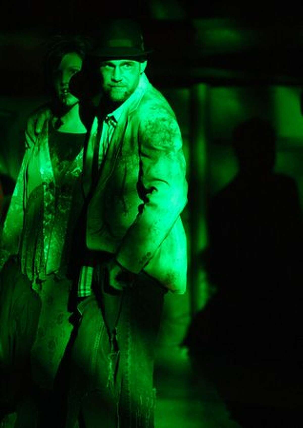 Zombie guests stand under a green spotlight during a wedding and wedding vow renewal ceremony.