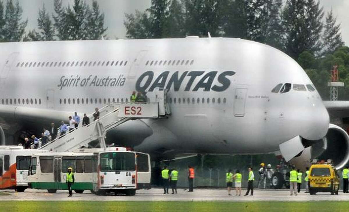 Passengers leave a troubled Qantas Airbus A380 plane after an emergency landing at the Changi International airport in Singapore.